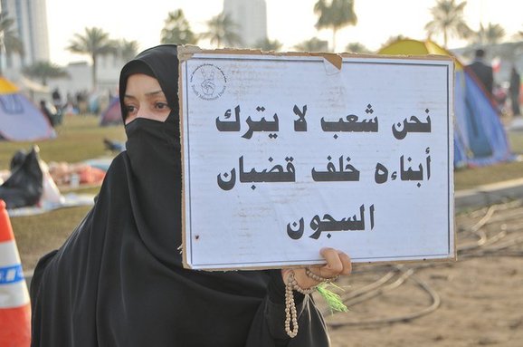 متظاهرة بحرينية ترفع لافتة متحدية متظاهرة بحرينية ترفع لافتة متحدية