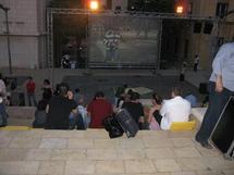 عدد من المشاهدين امام الشاشة في الهواء الطلق