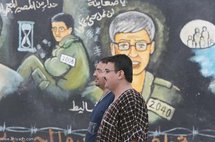 فلسطينيان يعبران امام لوحة جدارية في غزة للجندي الاسرائيلي جلعاد شاليط