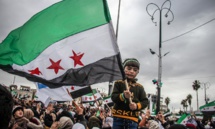 طفلة تحمل علم الثورة السورية خلال مظاهرة في مدينة إدلب لإحياء الذكرى الـ12 للثورة في سوريا- 15 من آذار 2023 (Mohamad Kazmooz/ فيس بوك)