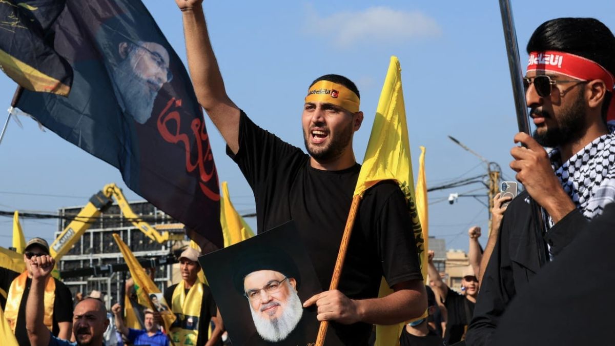 أحد مناصري حزب الله اللبناني يرفع علمًا عليه صورة الأمين العام السابق للحزب - 27 أيلول 2025 (رويترز)